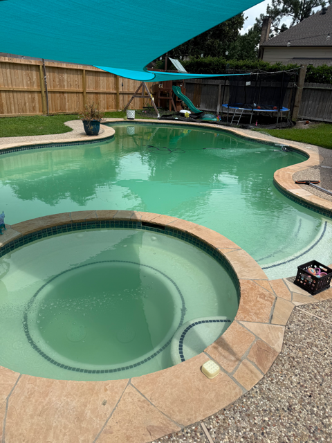 Cloudy green pool and attached spa in a fenced Houston backyard before chemical balancing and cleaning